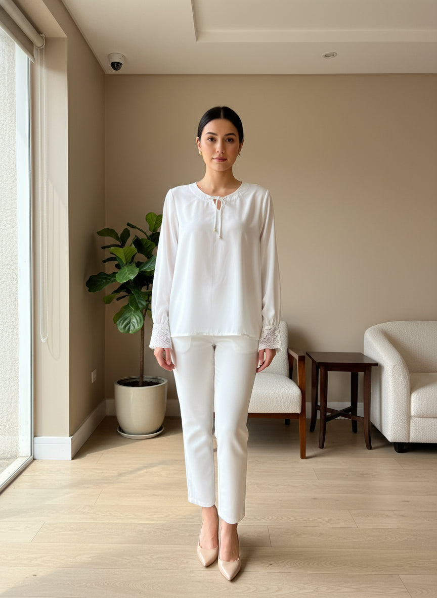 White blouse with lace details on a hanger against a neutral background